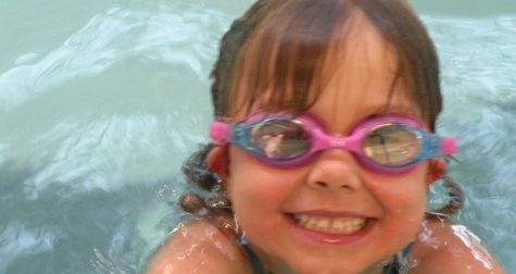 little girl in goggles in pool